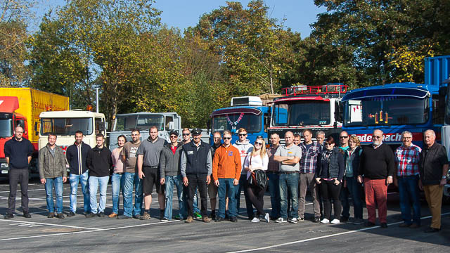 Gruppenbild vor einer Reihe von Oldtimer-LKWs.